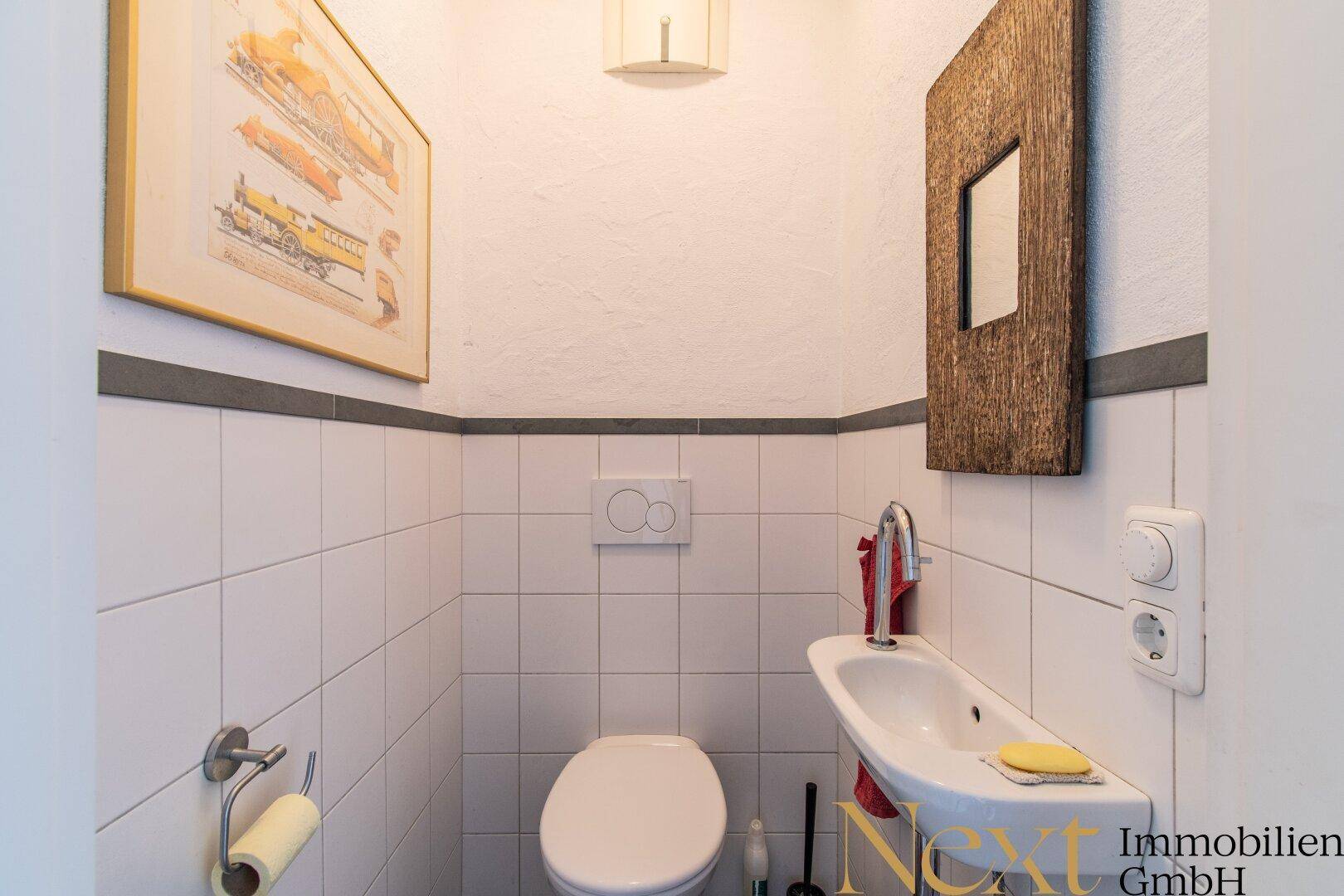 Kleines Gäste-WC mit weiß gefliesten Wänden, wandhängendem WC und kleinem Waschbecken.