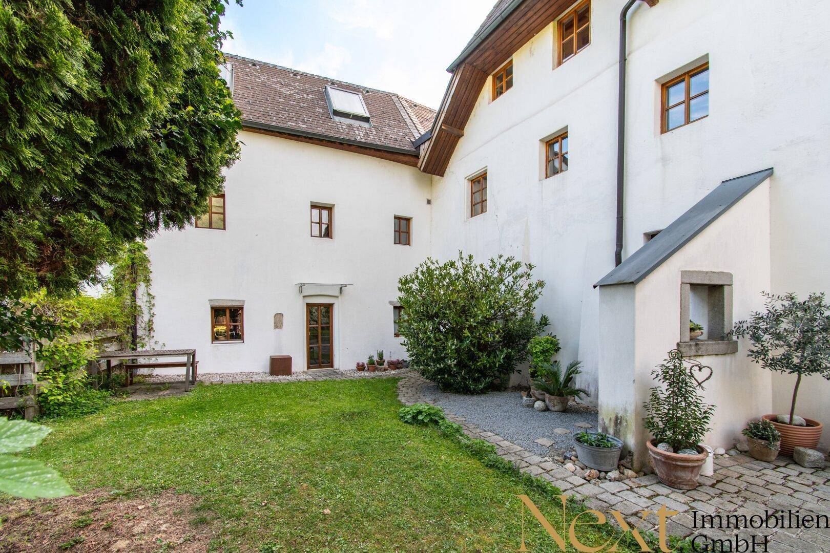 Weitläufiger Gartenbereich mit Rasen, Kiesweg und der historischen Fassade des Gebäudes.