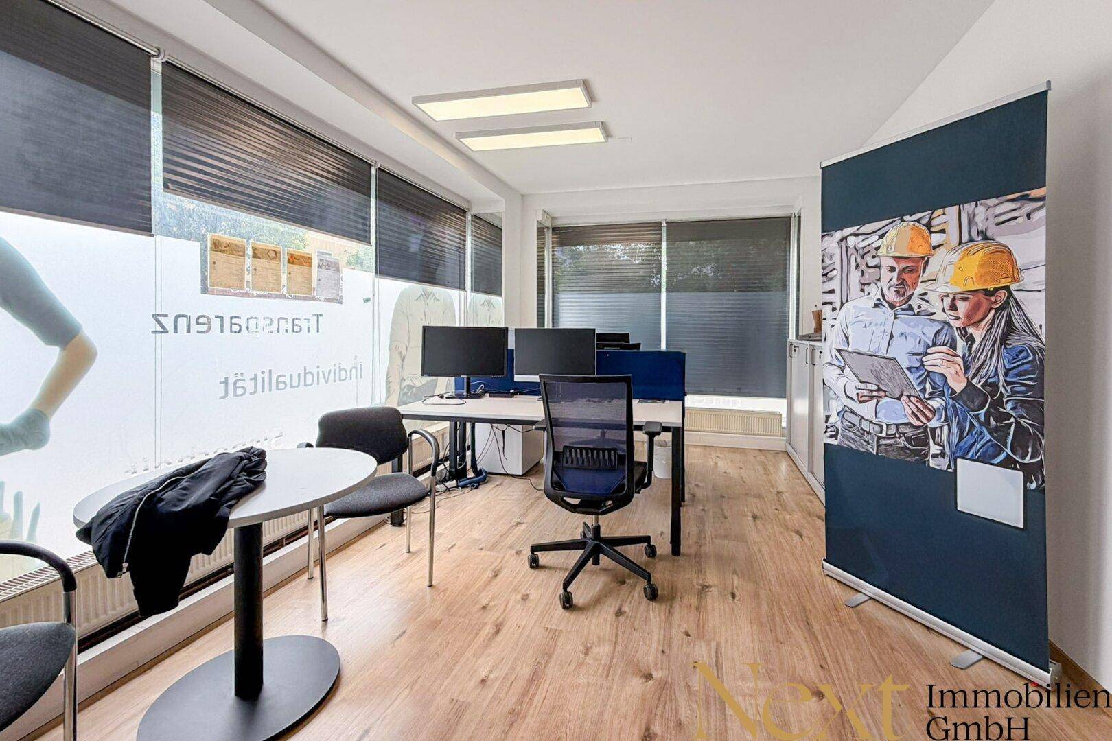 Moderner Bürobereich mit Arbeitsplätzen, Besprechungstisch und großen Fenstern mit Sichtschutzfolie.