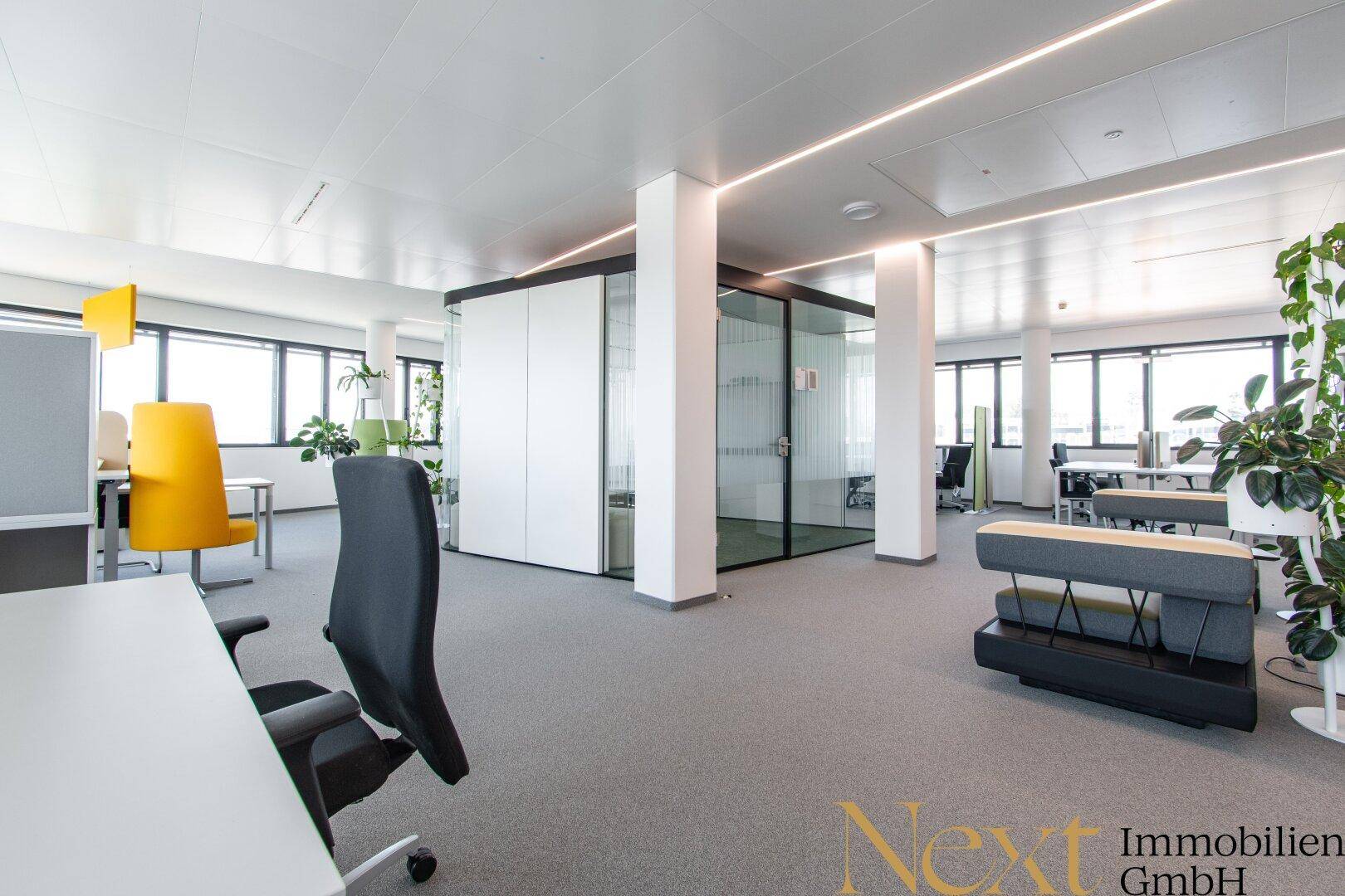 Helles und geräumiges Büro mit modernen Arbeitsbereichen, Glaswänden und integrierter Beleuchtung.