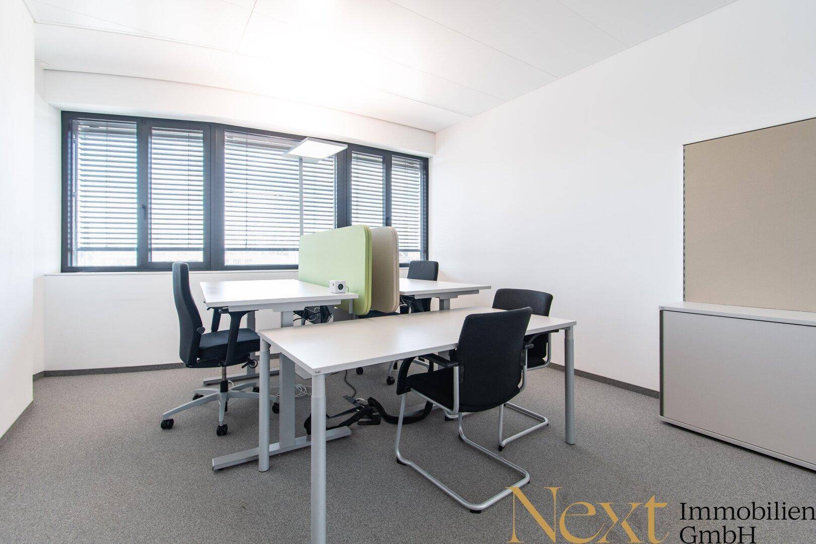 Einzelbüro mit zwei Arbeitsplätzen, großen Fenstern und Jalousien für Privatsphäre.