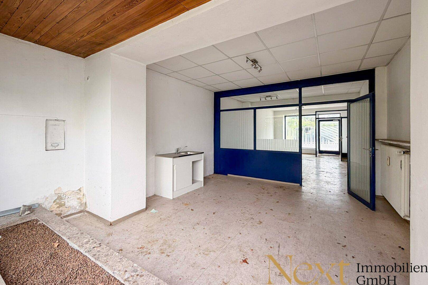 Bürofläche mit Teppichboden, Holzdecke und einer blauen Glaswandabtrennung.
