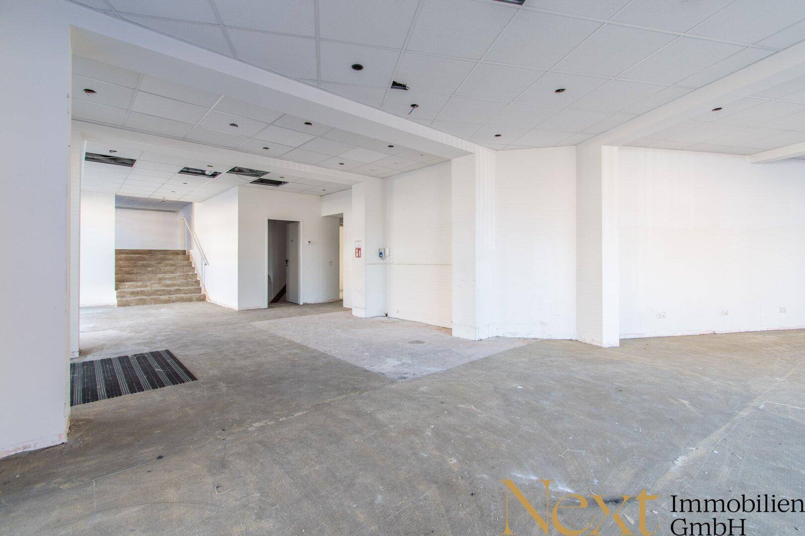 Großer, offener Innenraum mit Betonboden und abgehängter Decke, bereit für den Ausbau.