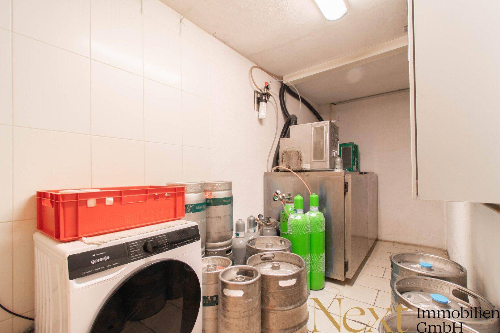 Technikraum mit Bierfässern, Gasflaschen und einer Waschmaschine.