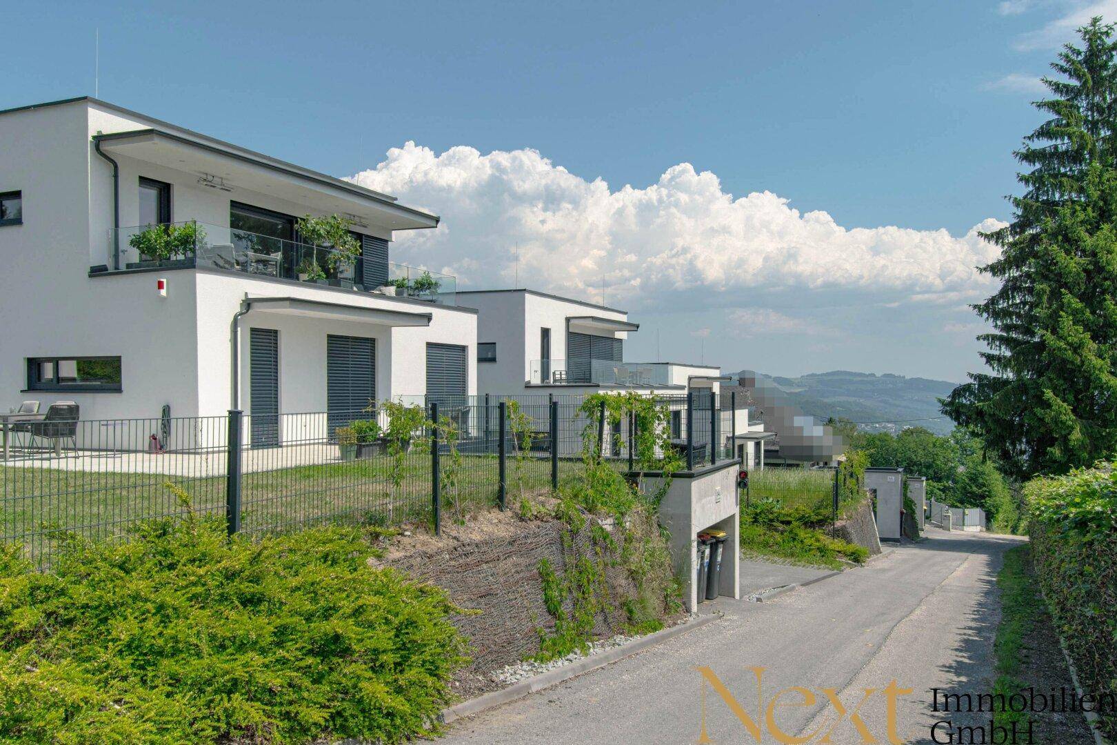 Moderne Wohngebäude am Hang mit Terrassen und Blick in die Landschaft.