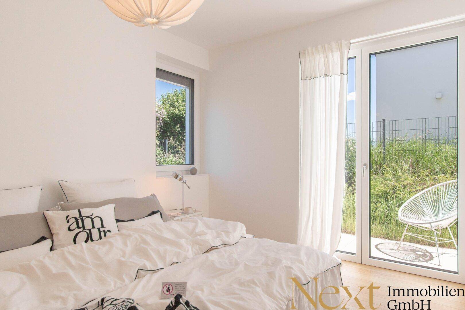 Helles Schlafzimmer mit Zugang zu einem Außenbereich und Blick ins Grüne.