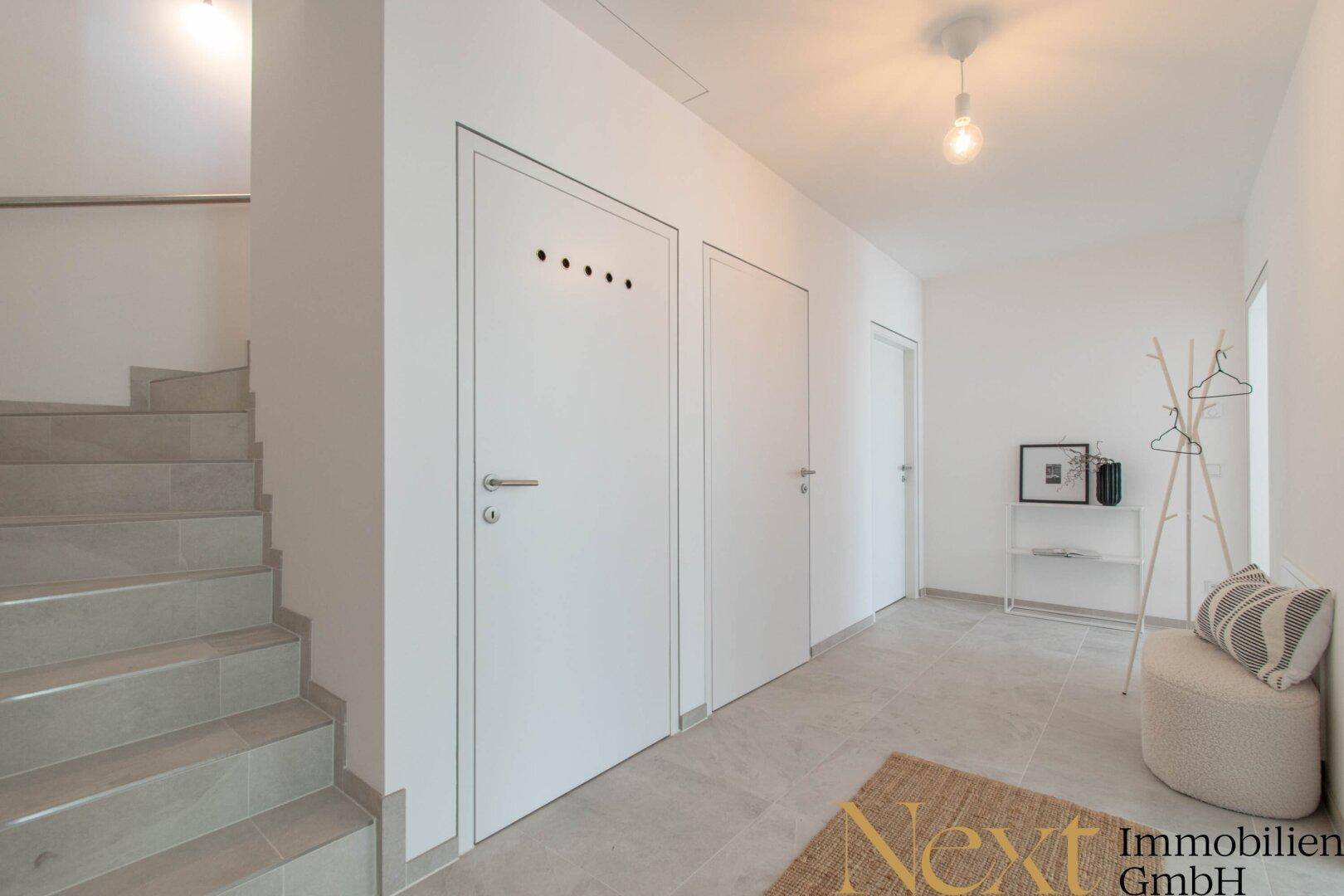 Geräumiger Flur mit Treppe, Fliesenboden und mehreren Türen.
