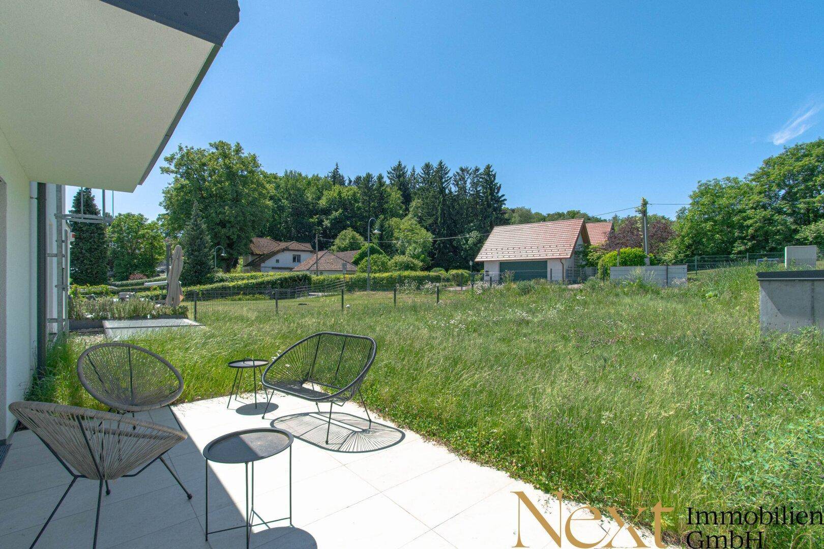 Sonniger Terrassenbereich mit Sitzgelegenheiten und weitem Blick ins Grüne.