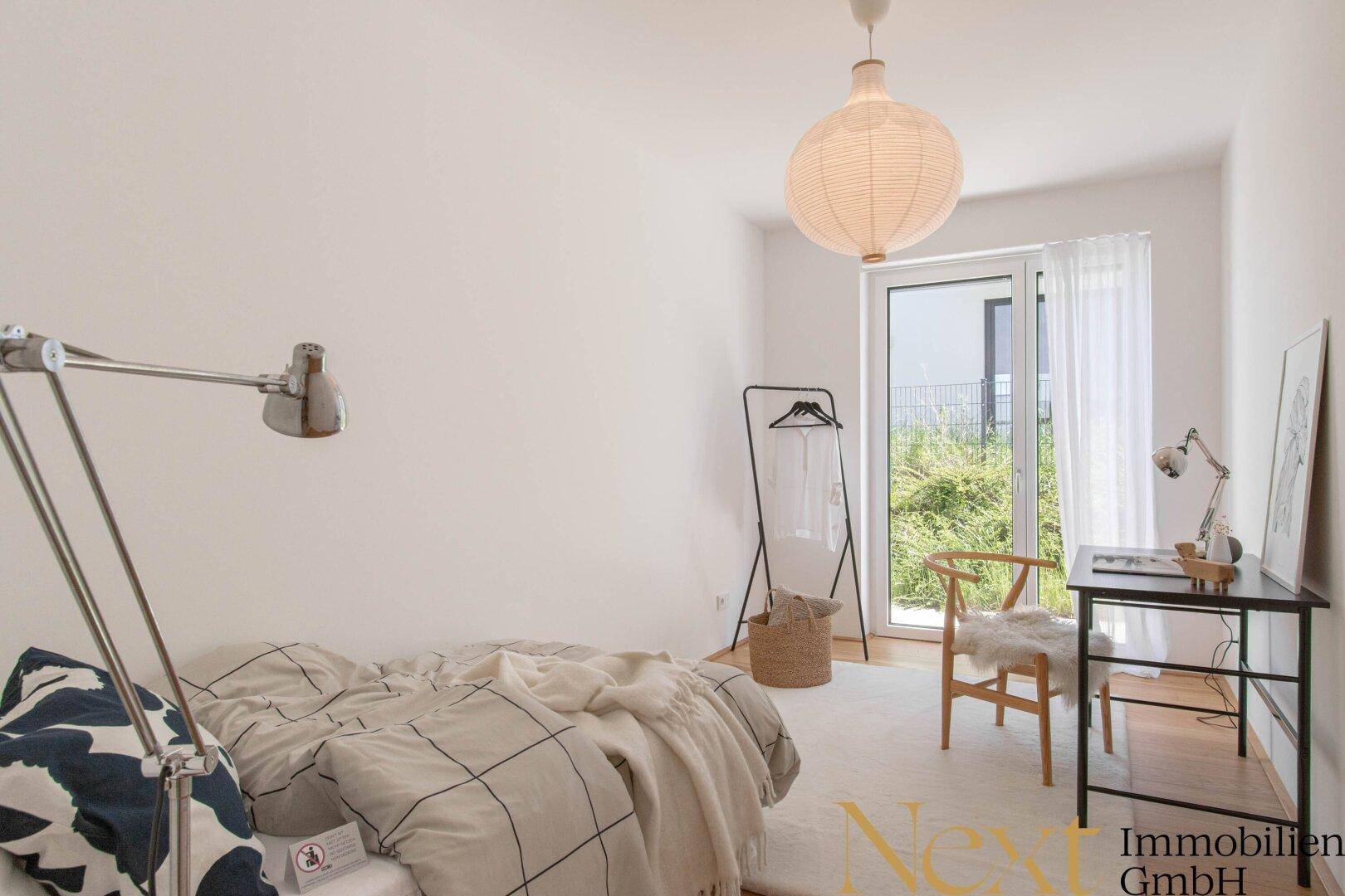 Helles Zimmer mit Schreibtisch, Holzboden und Zugang zum Außenbereich.
