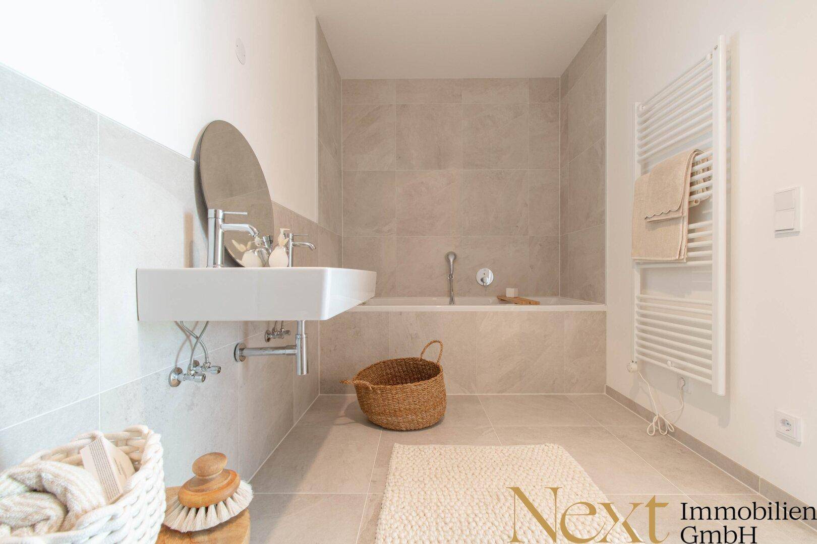 Modernes Badezimmer mit hellen Fliesen, Badewanne und beheiztem Handtuchhalter.