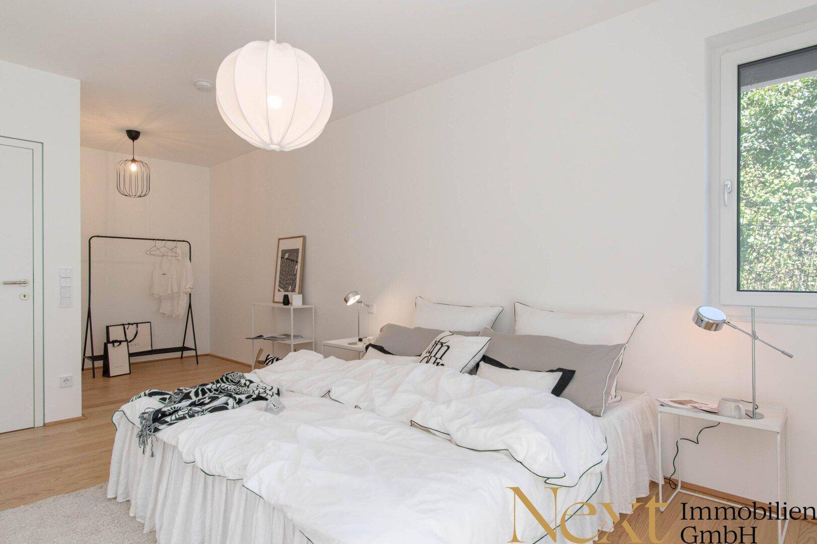 Modernes Schlafzimmer mit Holzboden, großem Bett und viel Tageslicht.