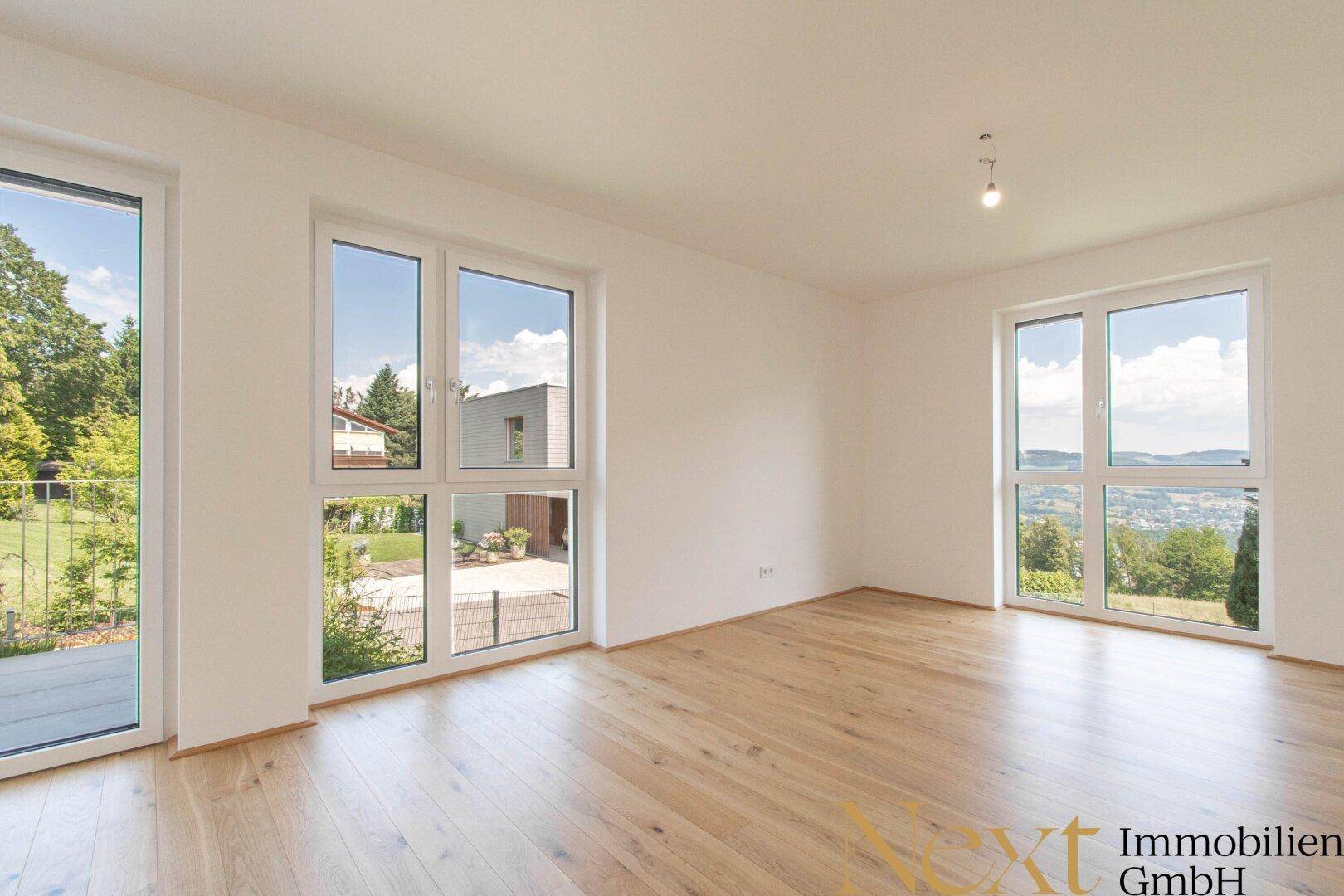 Lichtdurchfluteter Raum mit Holzboden und weitem Ausblick, ideal als Wohn- oder Essbereich.