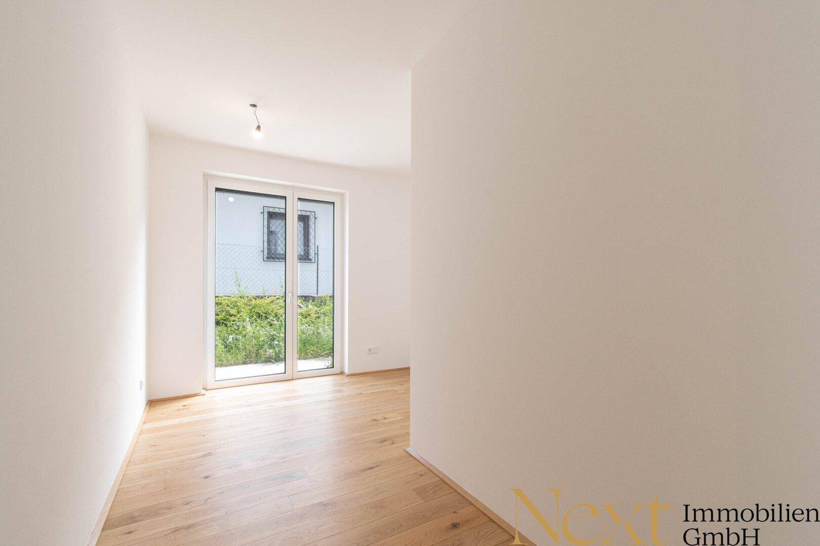 Kleinerer, heller Raum mit Parkettboden und Zugang zu einem Außenbereich, ideal als Kinderzimmer.