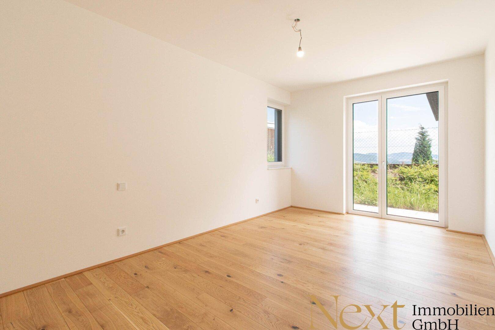 Helles Schlafzimmer mit Holzboden und großem Fenster, das einen weiten Blick bietet.