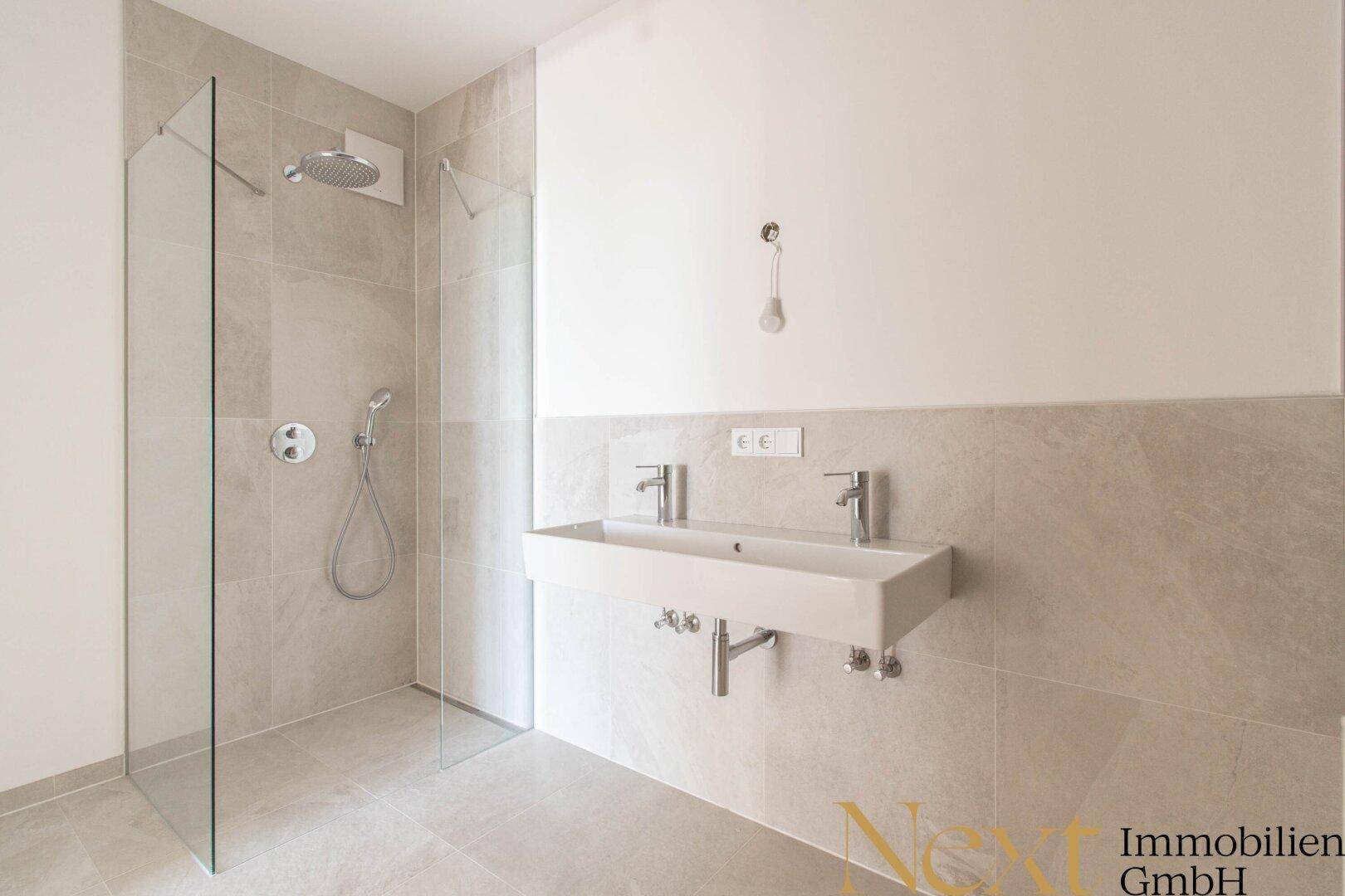 Modernes Badezimmer mit begehbarer Dusche, Doppelwaschbecken und hellen Fliesen.