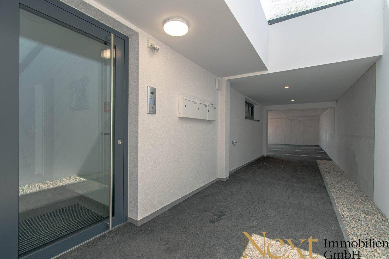 Moderner Eingangsbereich mit Aufzug und Zugang zu einer Tiefgarage oder Keller.