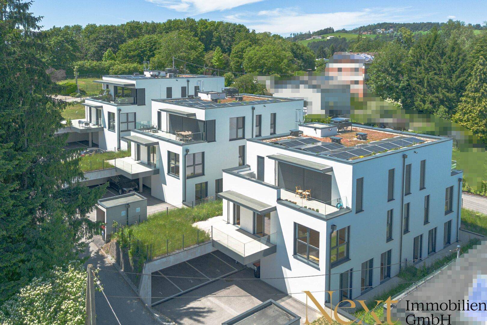 Luftaufnahme einer modernen Wohnanlage mit mehreren Gebäuden, Terrassen und Solaranlagen.