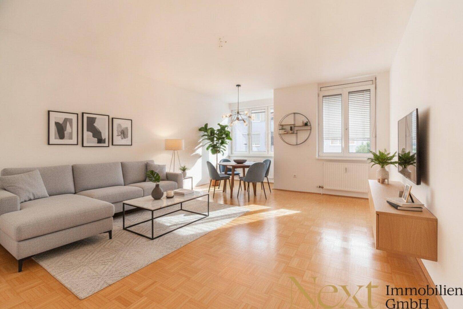 Lichtdurchfluteter Wohn-Essbereich mit bequemer Couch, Esstisch und Parkettboden, schafft eine einladende Atmosphäre.