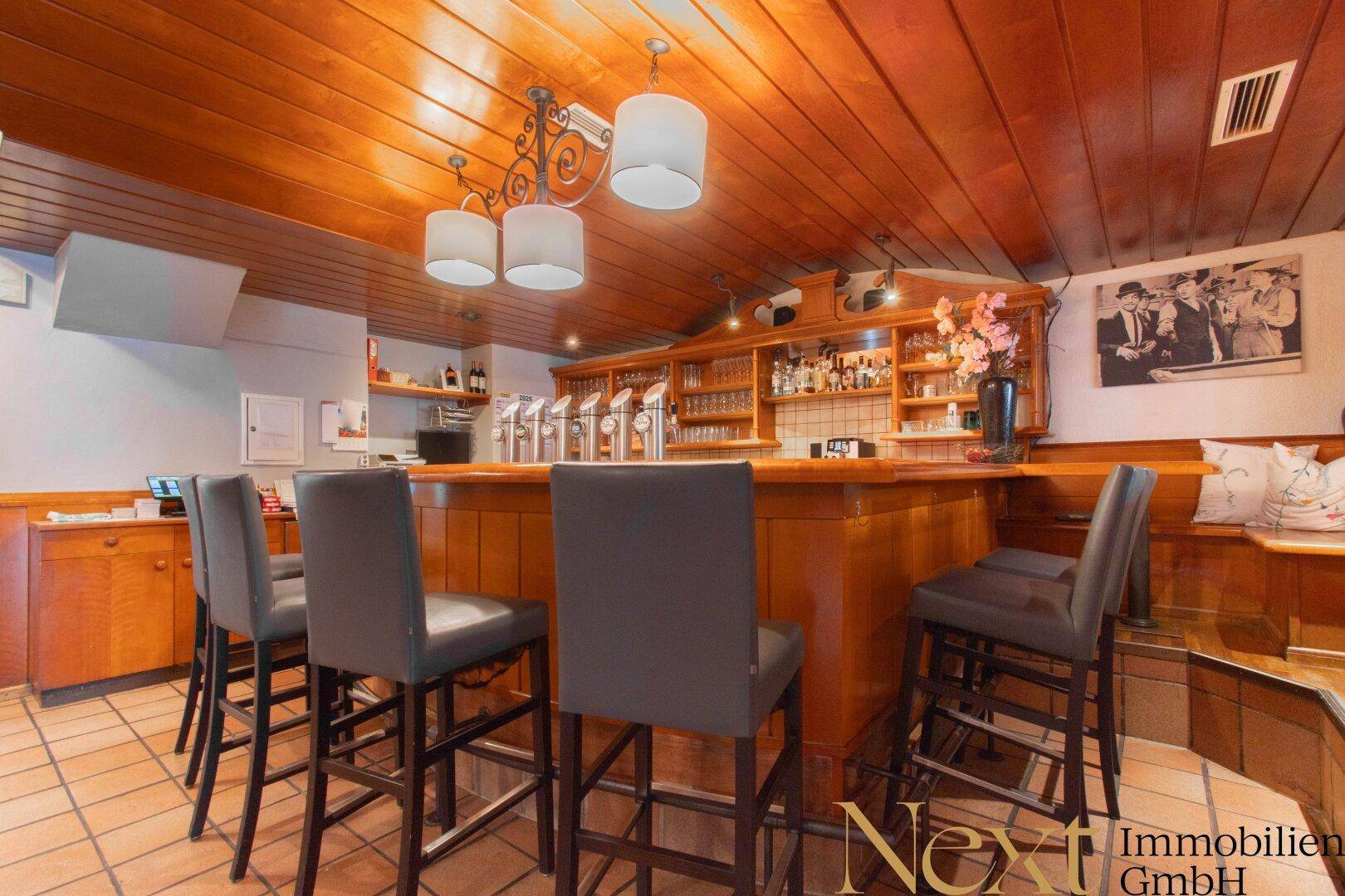 Rustikale Bar mit Holzelementen, Barhockern und Zapfanlage.
