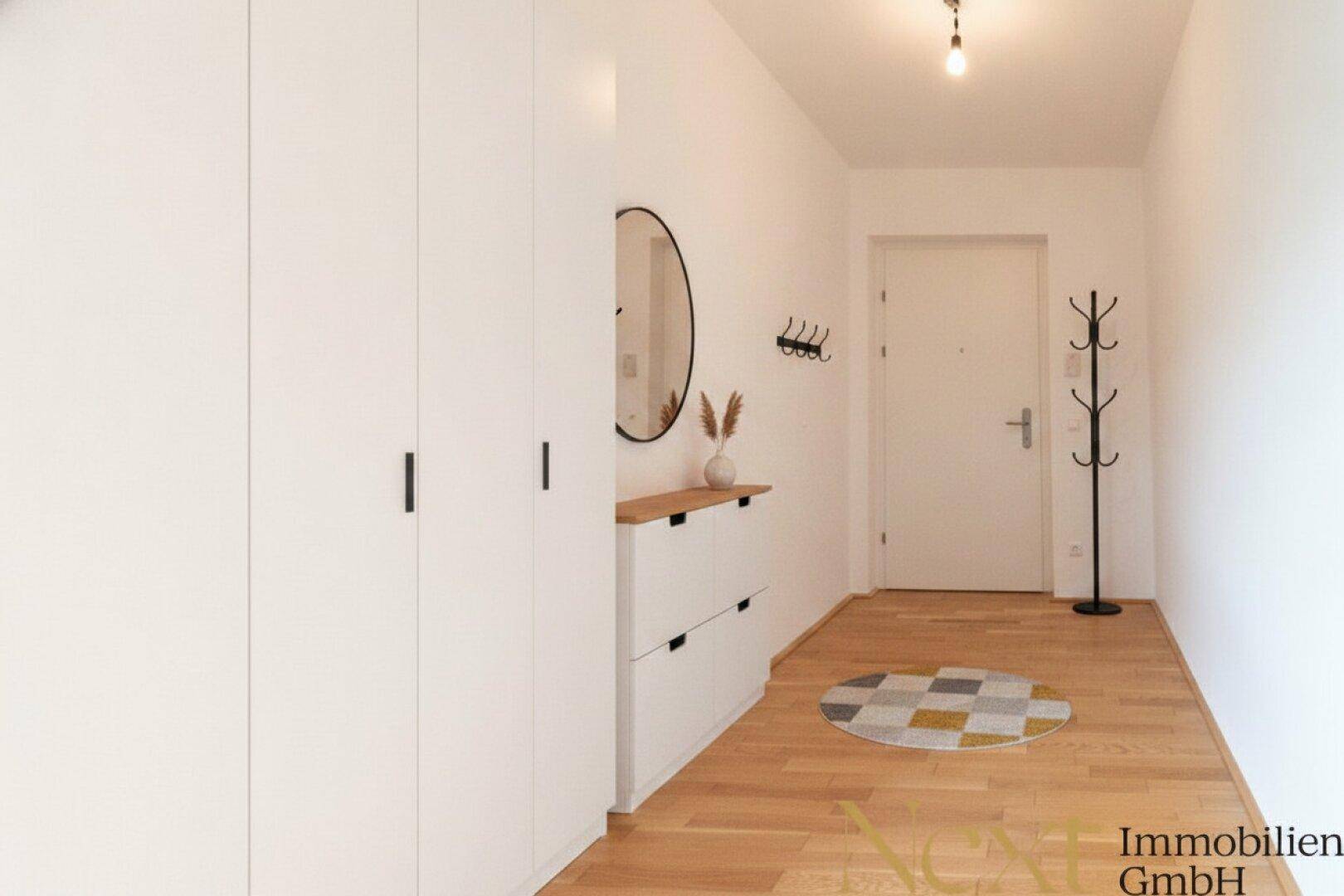 Freundlicher Eingangsbereich mit Garderobe, Spiegel und Schuhschrank auf Parkettboden.