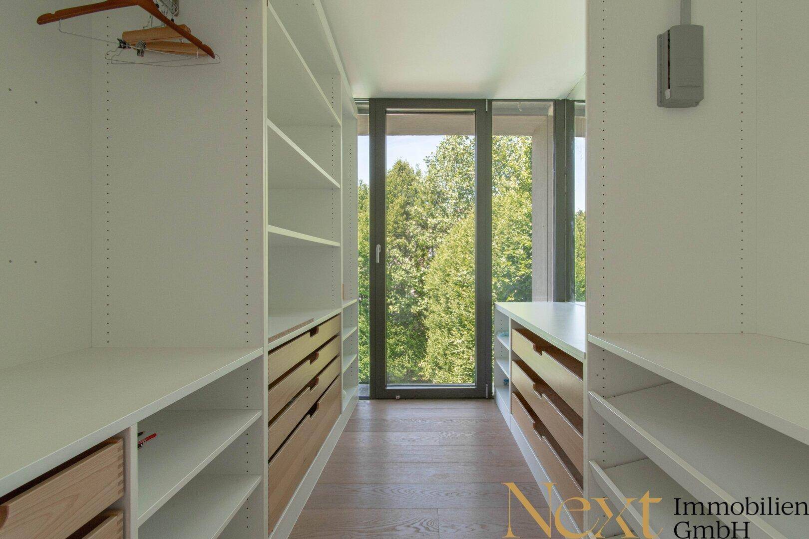 Begehbarer Kleiderschrank mit Einbauschränken und Fenster, das Tageslicht und Grünblick bietet.