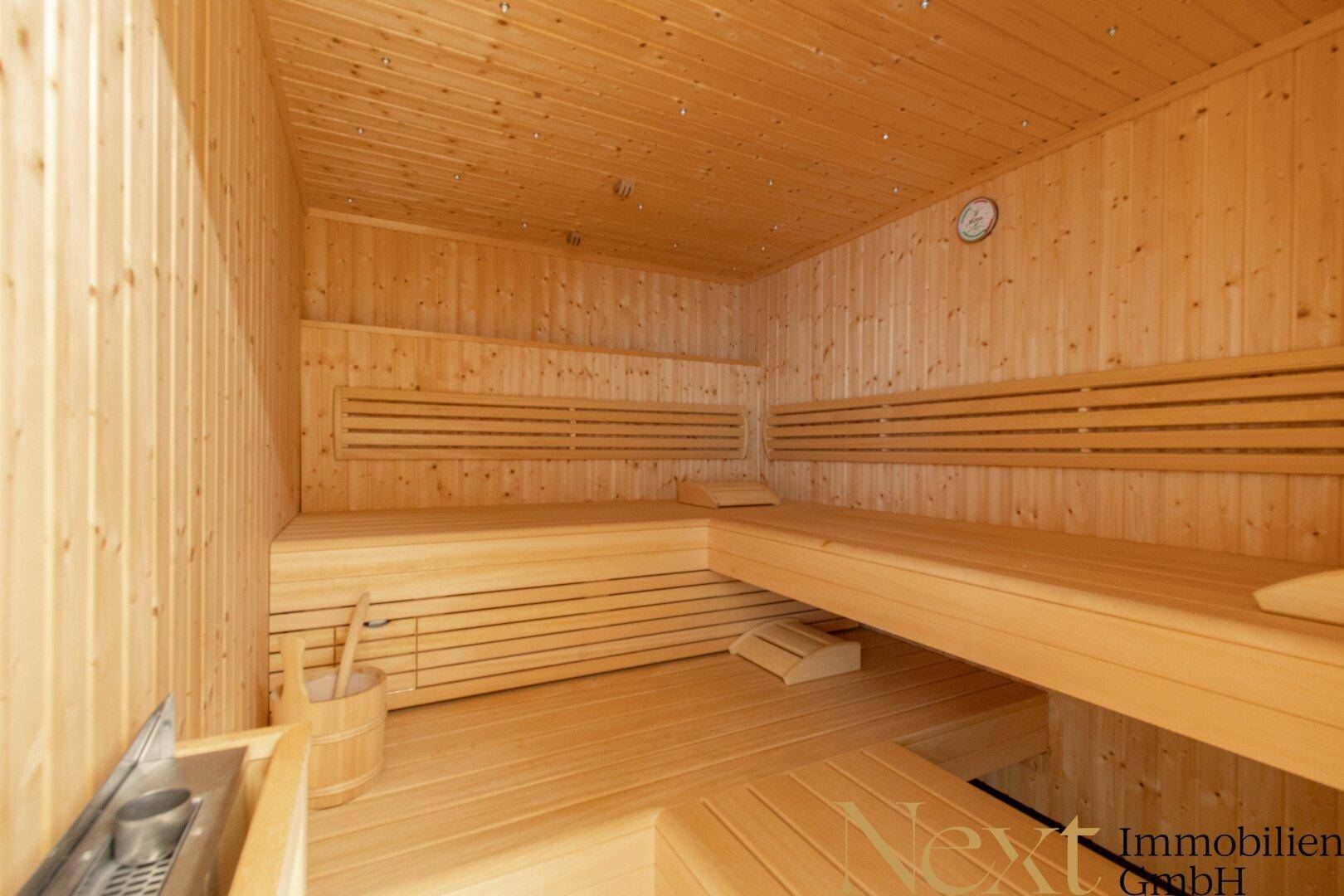 Traditionelle Holzsauna mit mehreren Bänken und einem Saunaofen für Entspannung.