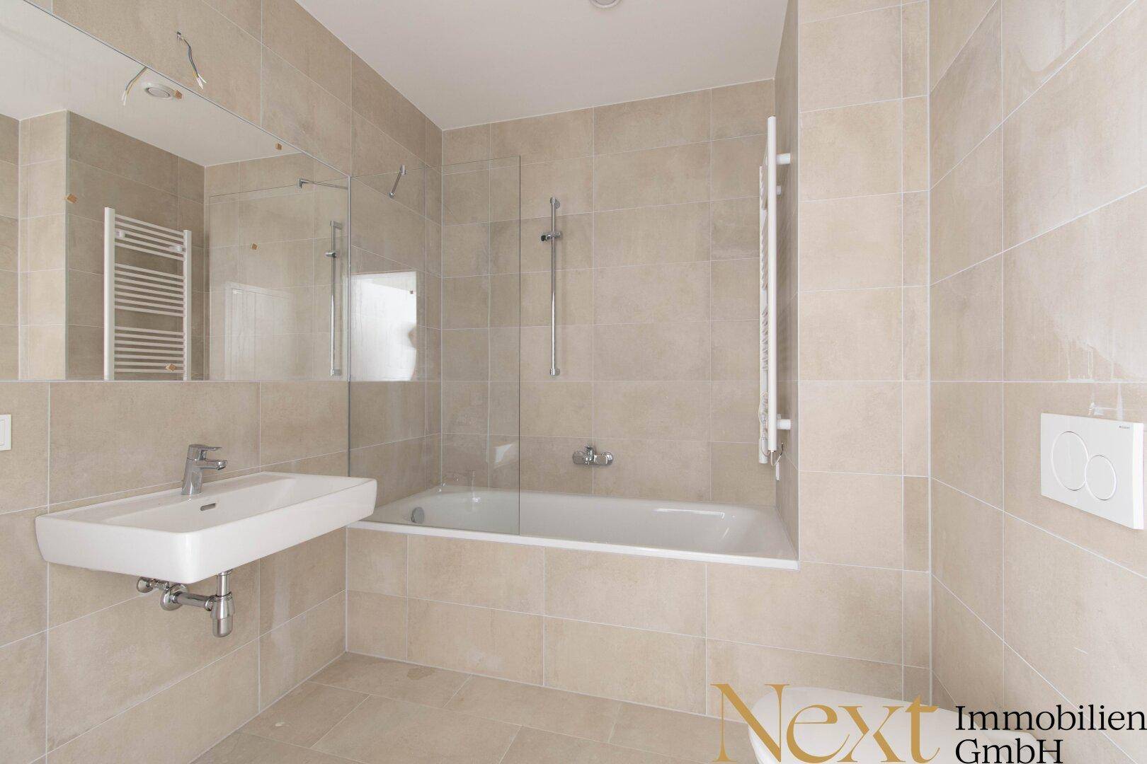 Modernes Badezimmer mit Badewanne, Duschfunktion, Einzelwaschbecken und beigefarbenen Fliesen.