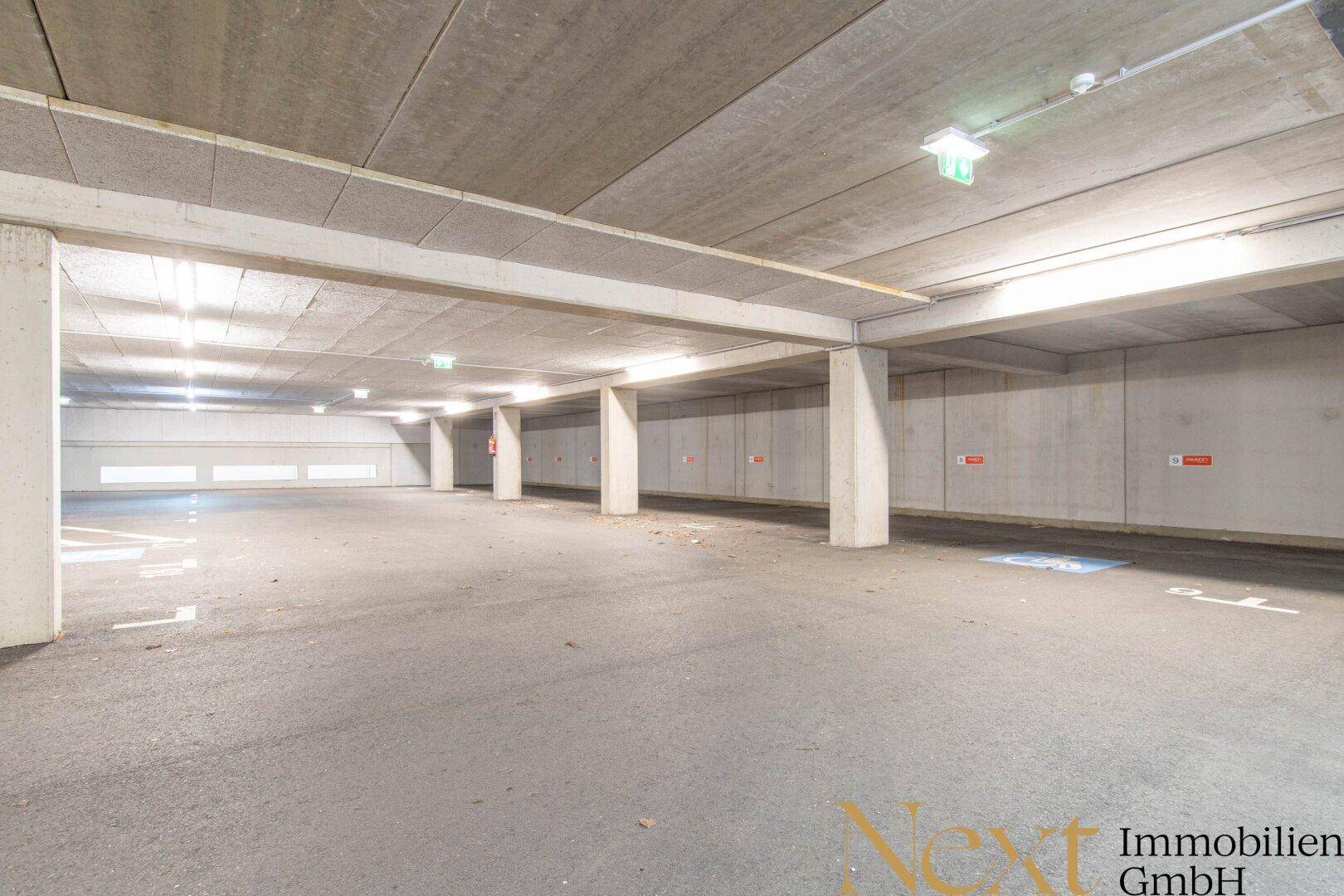 Geräumige Tiefgarage mit vielen Stellplätzen und klarer Beleuchtung, ideal für Bewohner und Besucher.