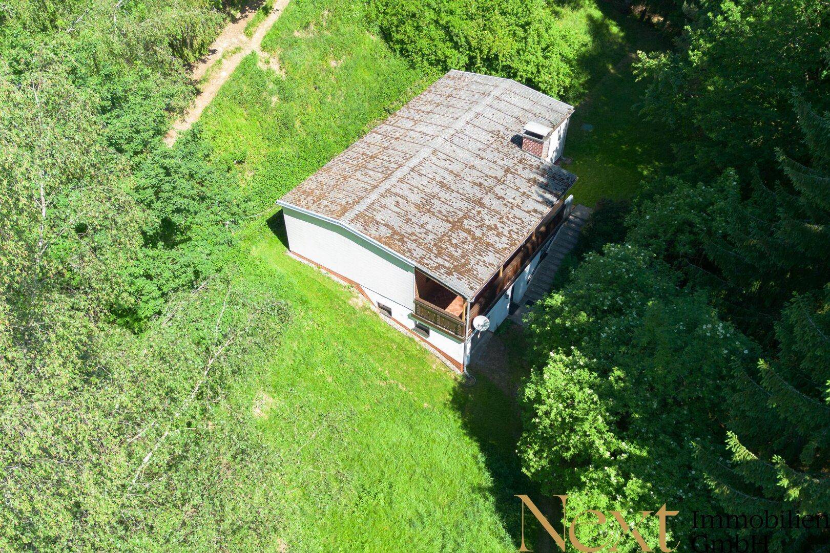 Vogelperspektive des Hauses in einer ruhigen, grünen Umgebung, umgeben von Bäumen und Natur.
