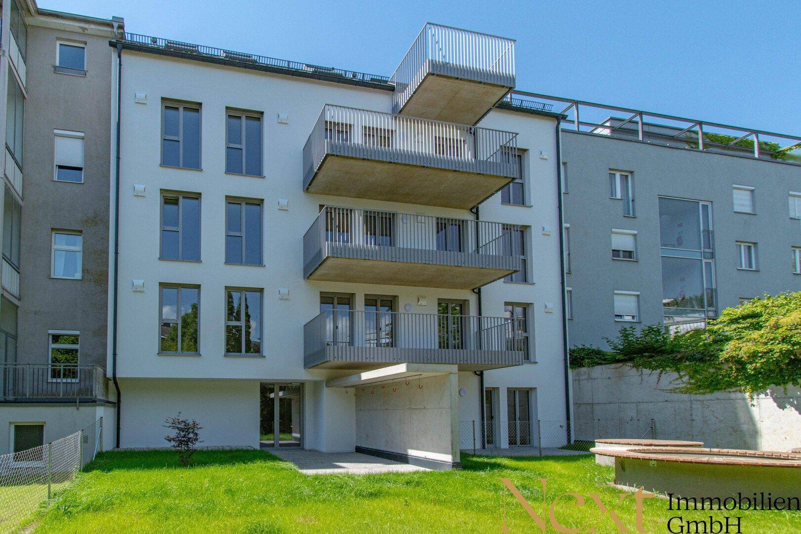 Moderne Wohnanlage mit mehreren Balkonen und einer gepflegten Rasenfläche im Vordergrund.