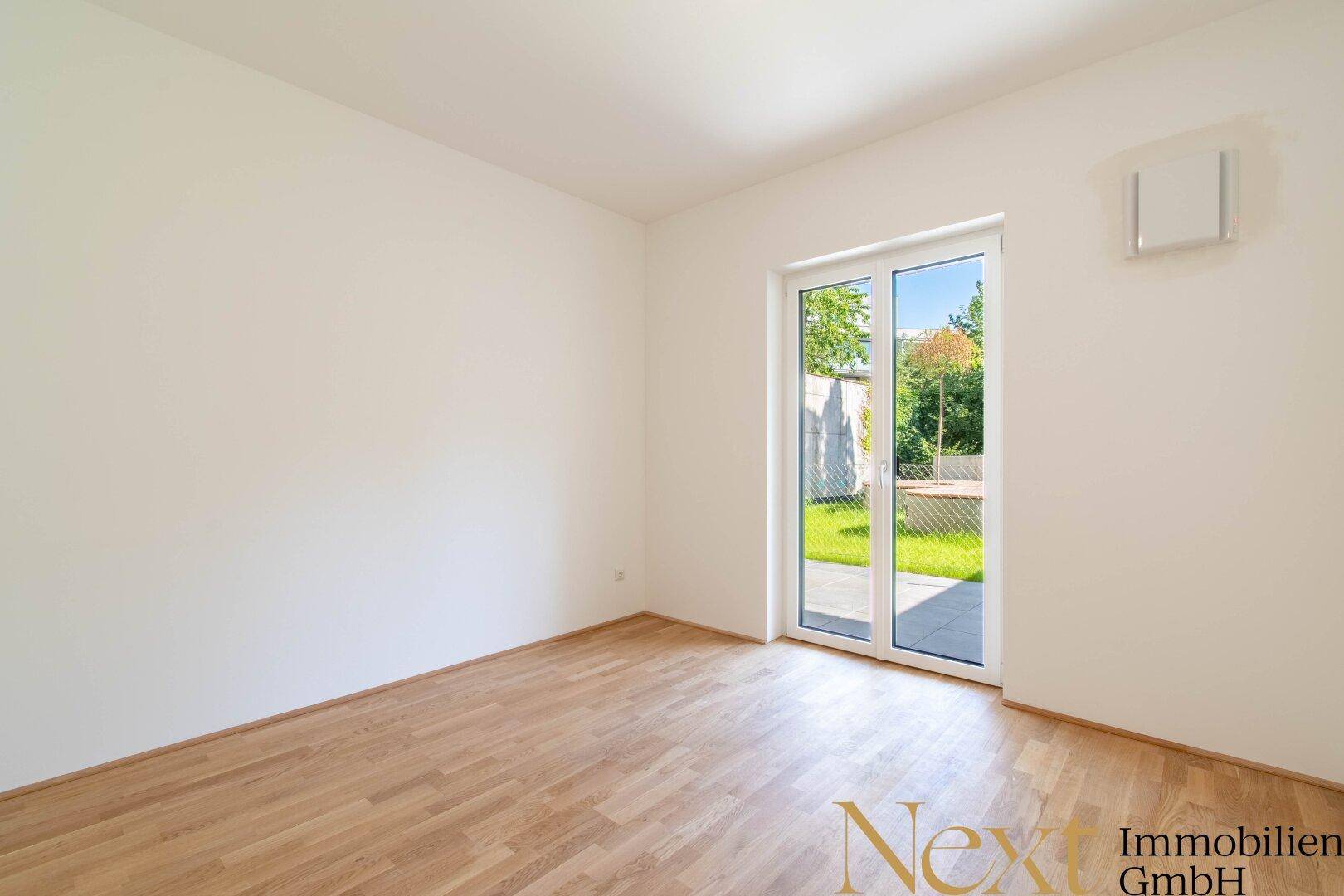 Helles Zimmer mit Holzboden und direktem Zugang zu einer Grünfläche im Freien.