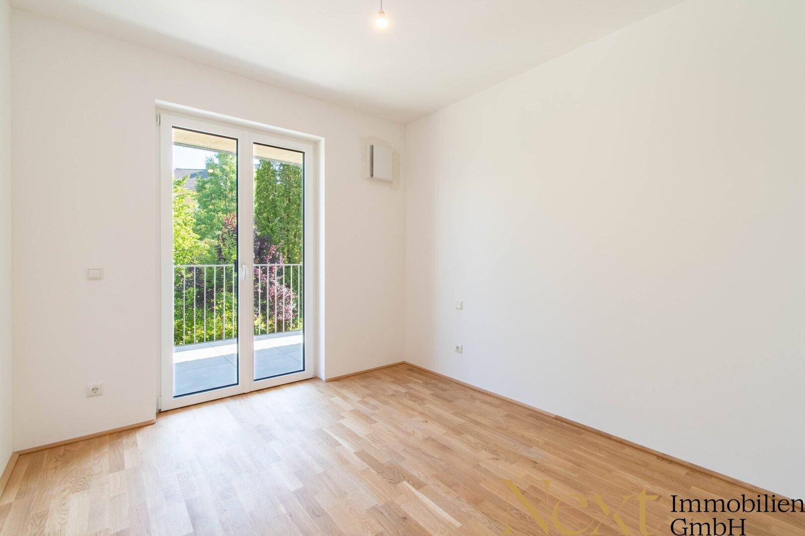 Geräumiges Schlafzimmer mit Parkettboden und Zugang zu einem französischen Balkon.