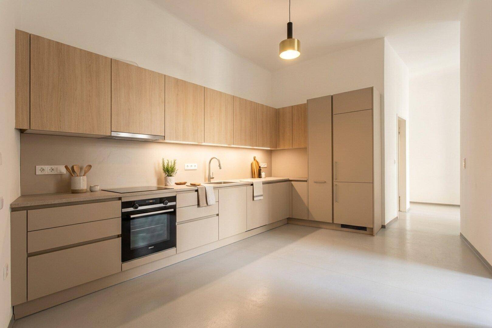 Moderne Einbauküche in Beige mit integrierten Geräten und hellem Boden.