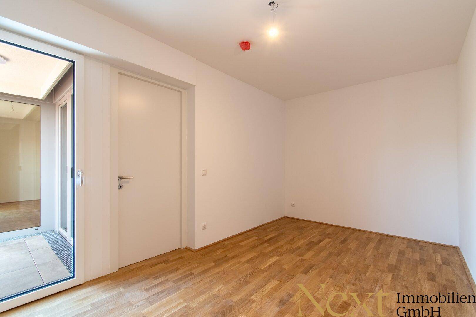 Freundliches Zimmer mit Parkettboden und Zugang zu einem Außenbereich, ideal für individuelle Nutzung.
