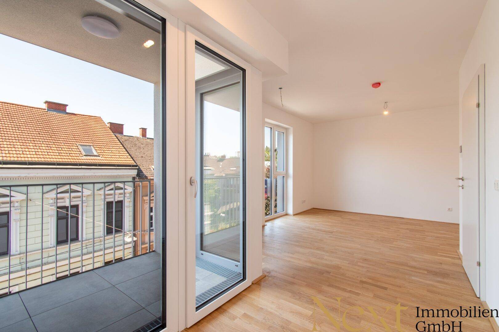 Lichtdurchflutetes Zimmer mit Parkettboden und direktem Zugang zu einem sonnigen Balkon.