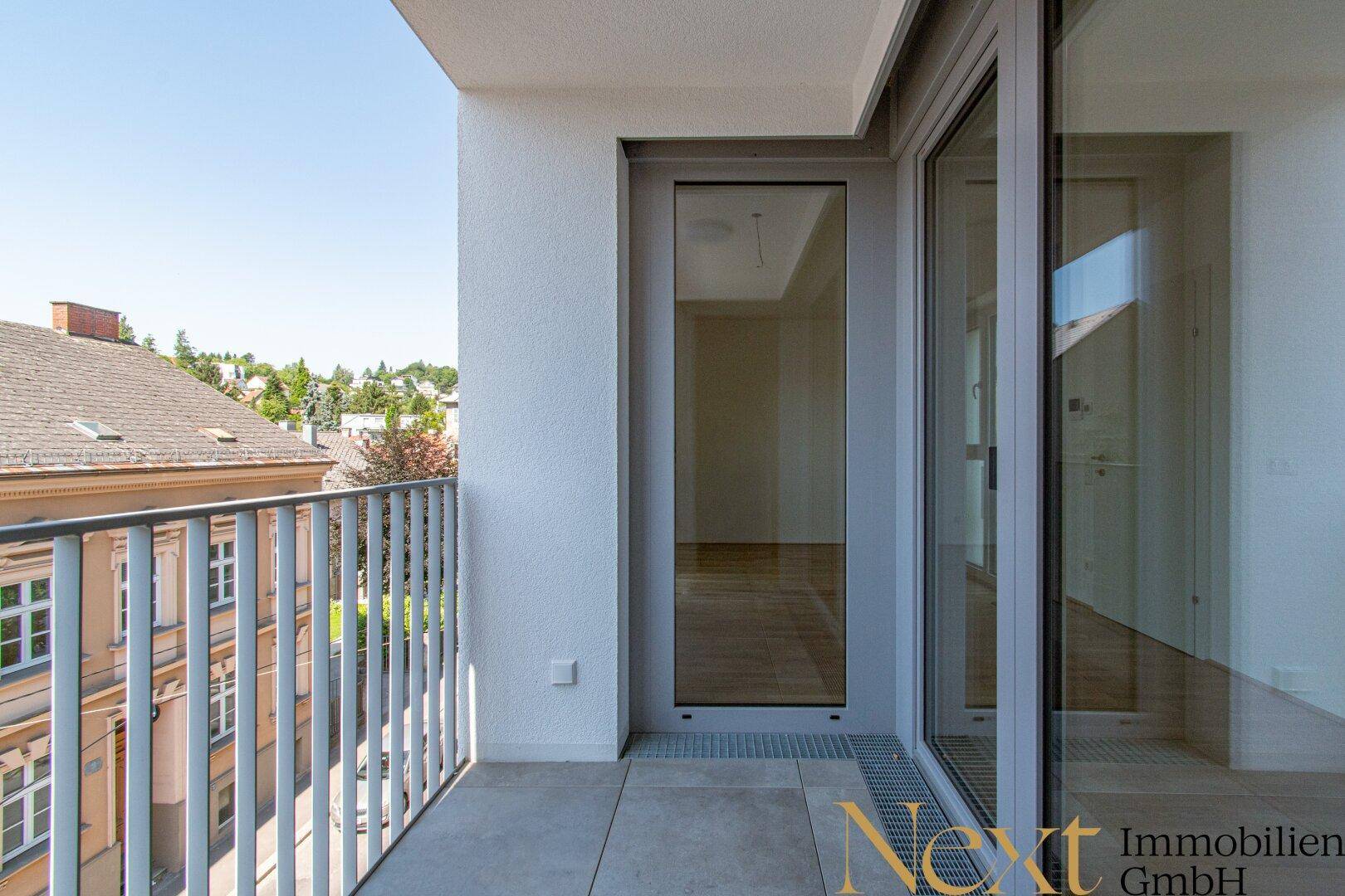Heller Balkon mit Fliesenboden und Blick auf die umliegenden Dächer und Gebäude der Stadt.