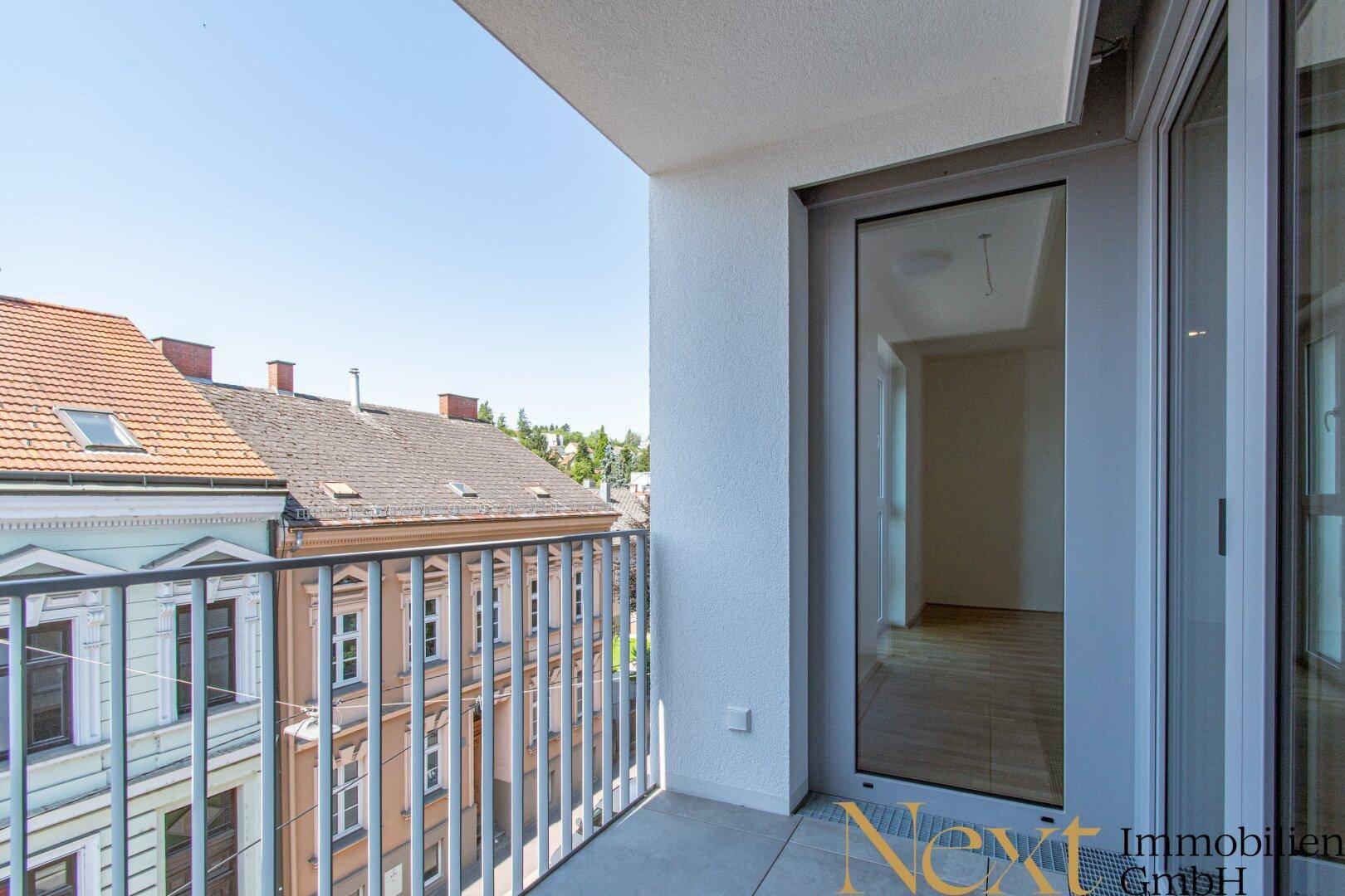 Sonniger Balkon mit Metallgeländer und weitem Blick über die historischen Dächer der Nachbarschaft.