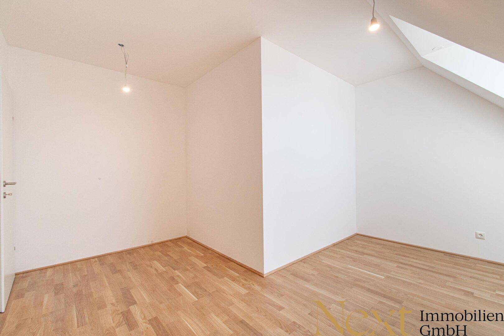 Unmöblierter Raum mit Holzboden und schrägen Wänden, ideal für ein Schlafzimmer oder Büro.