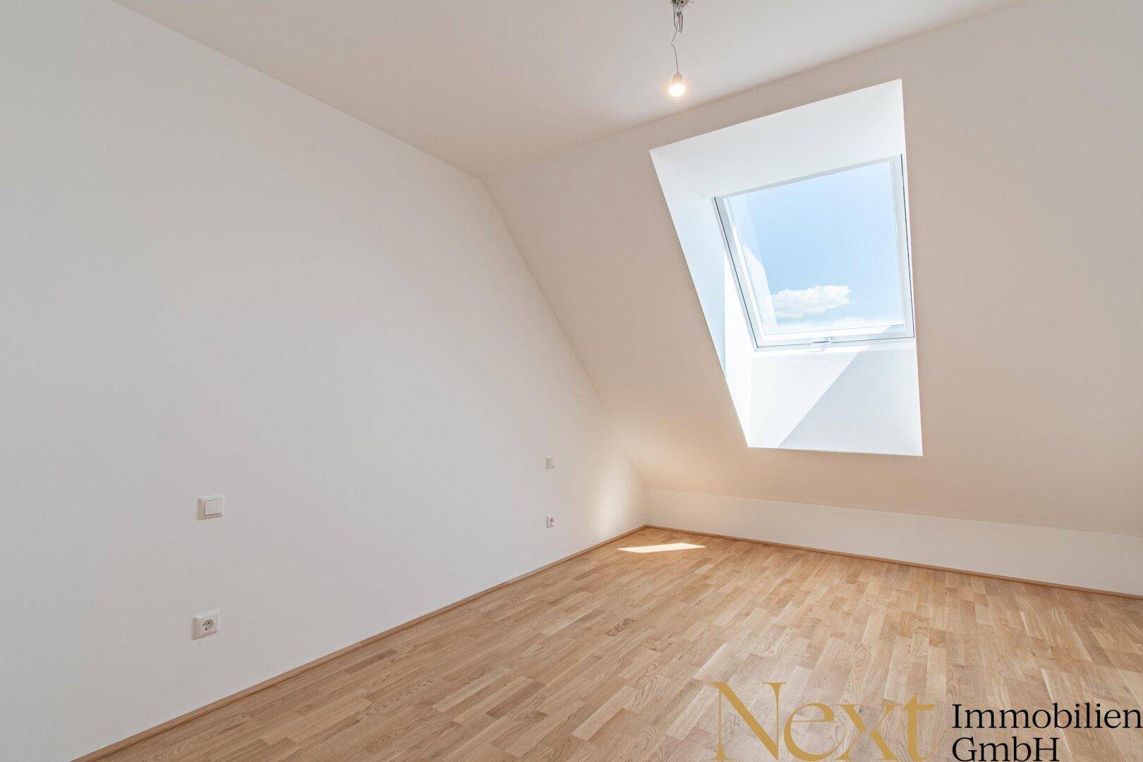 Heller Raum mit Holzboden und einem großen Dachfenster, das viel Tageslicht hereinlässt.