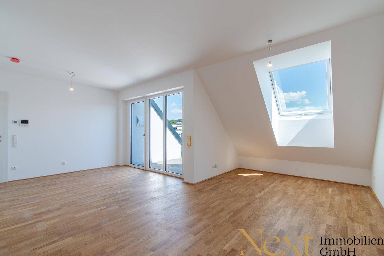 Heller Wohnraum mit Holzboden, großen Schiebetüren zur Terrasse und einem Dachfenster für viel Licht.