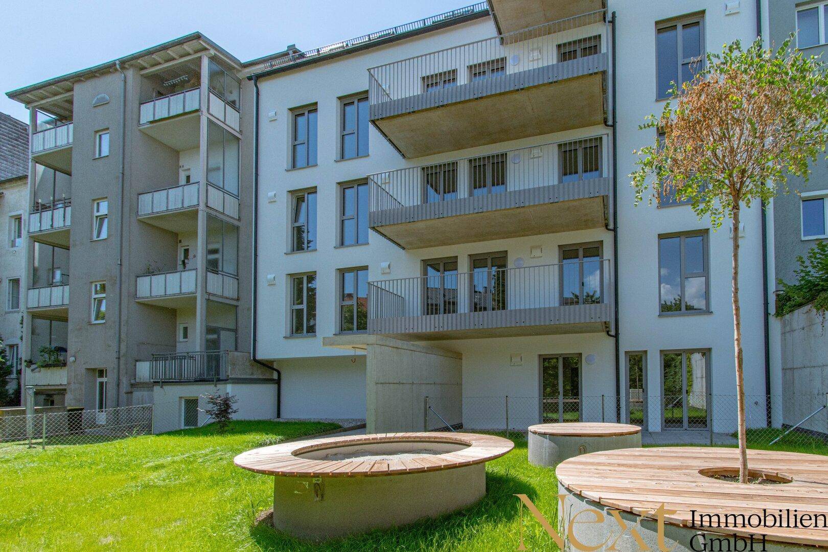 Moderne Wohnanlage mit Balkonen und einem gepflegten Gemeinschaftsgarten im Vordergrund.
