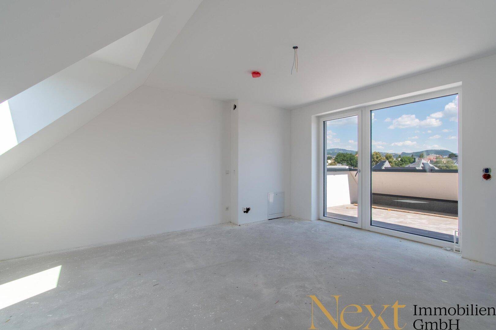 Heller Raum mit großer Glasfront und Zugang zu einer Terrasse oder einem Balkon.