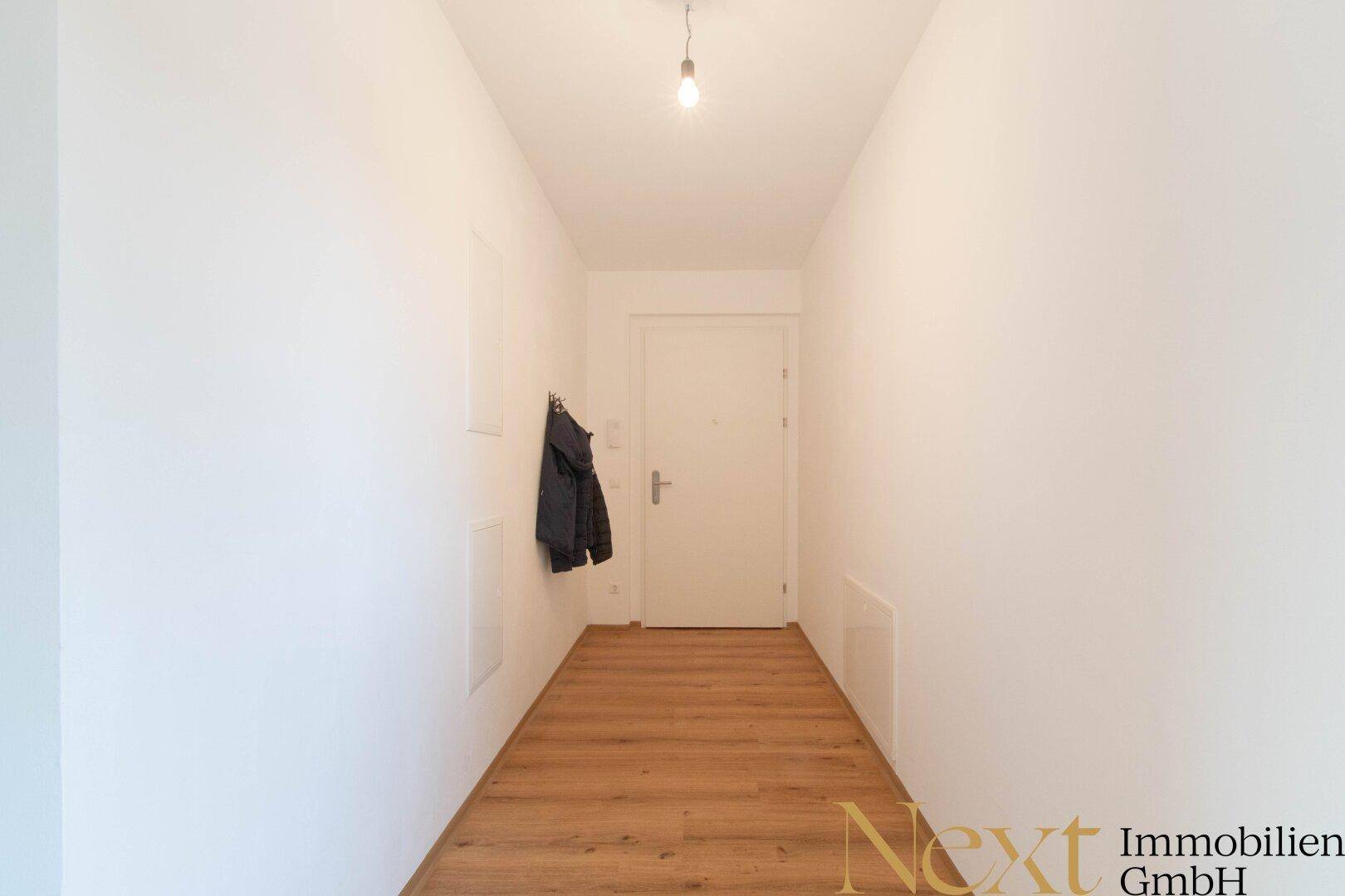 Heller Flur mit Laminatboden und Garderobenbereich, der zum Eingang führt.