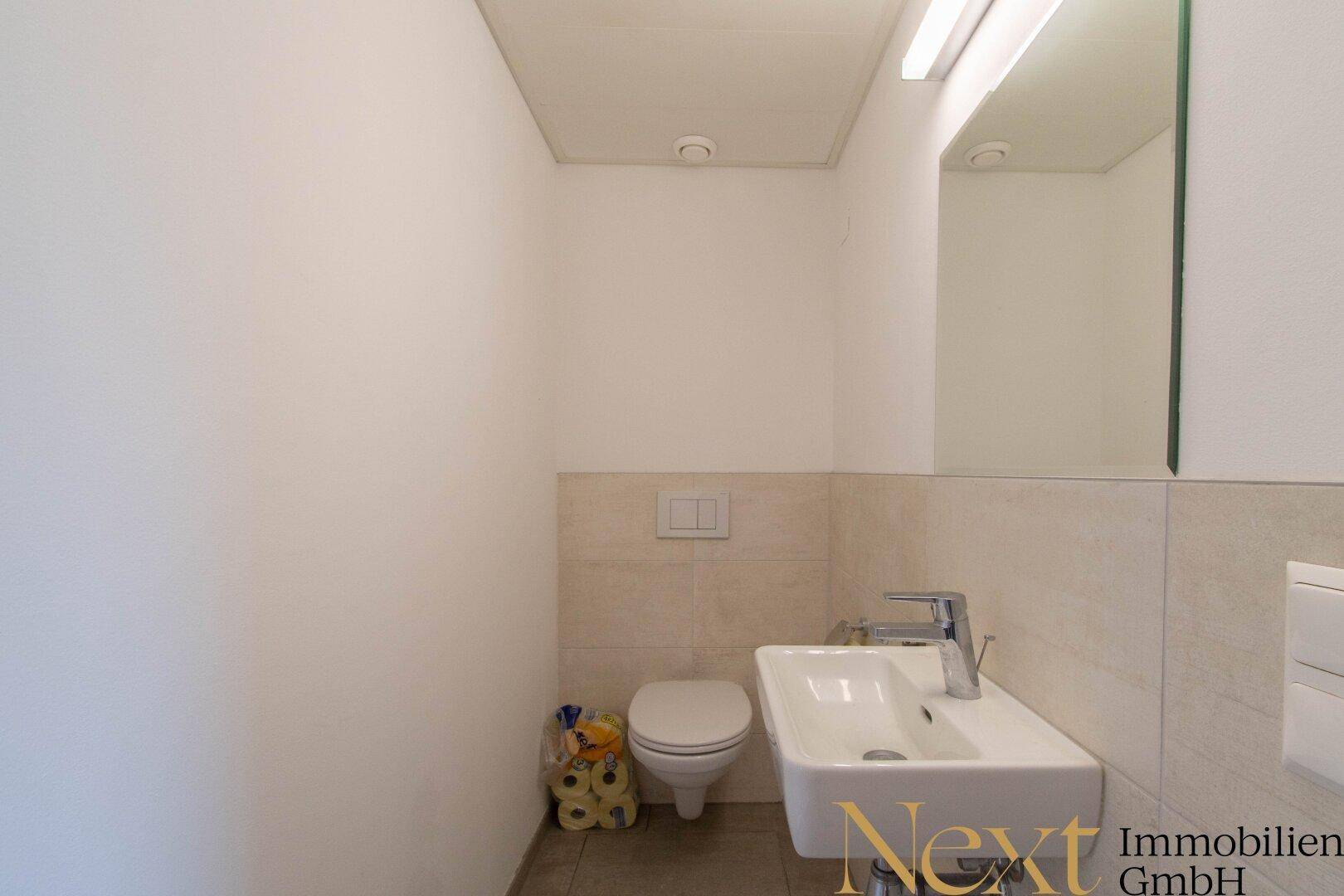 Separates Gäste-WC mit modernem Waschbecken und wandhängender Toilette.