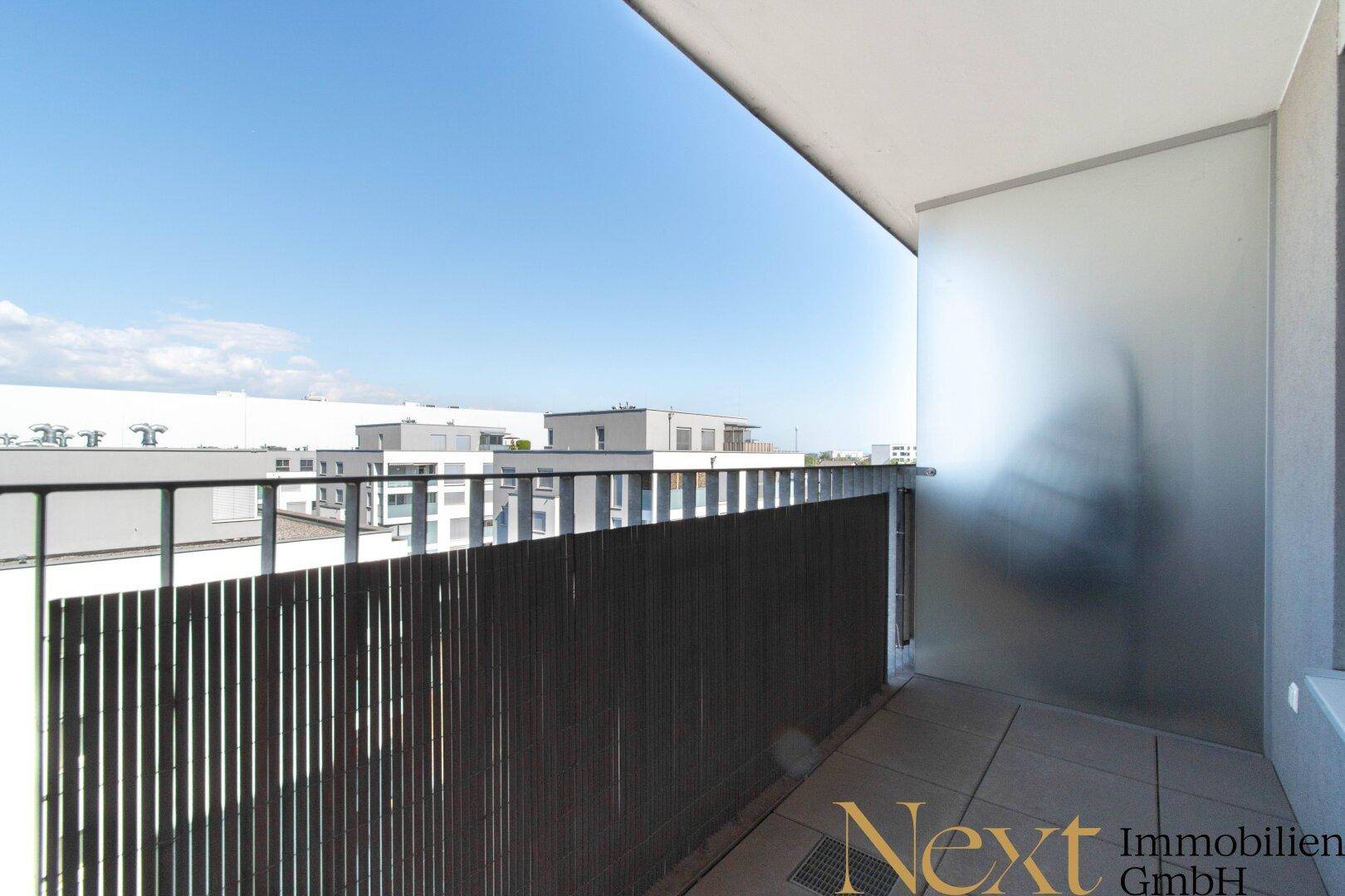 Balkon mit Blick auf umliegende Gebäude und den Himmel, ideal für Entspannung im Freien.
