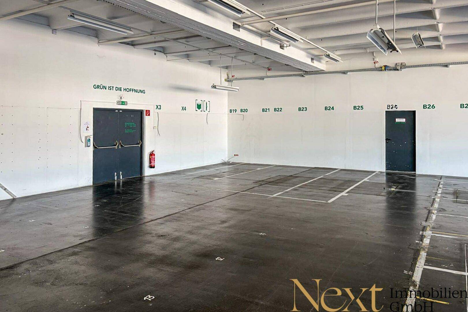 Großer, heller Raum mit industriellem Charme, hohen Decken und funktionalen Türen, bereit zur individuellen Nutzung.