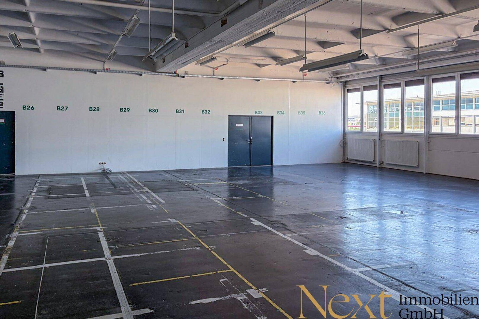 Weitläufiger Gewerberaum mit hohen Decken, großen Fenstern und robustem Boden, ideal für vielfältige Geschäftsideen.