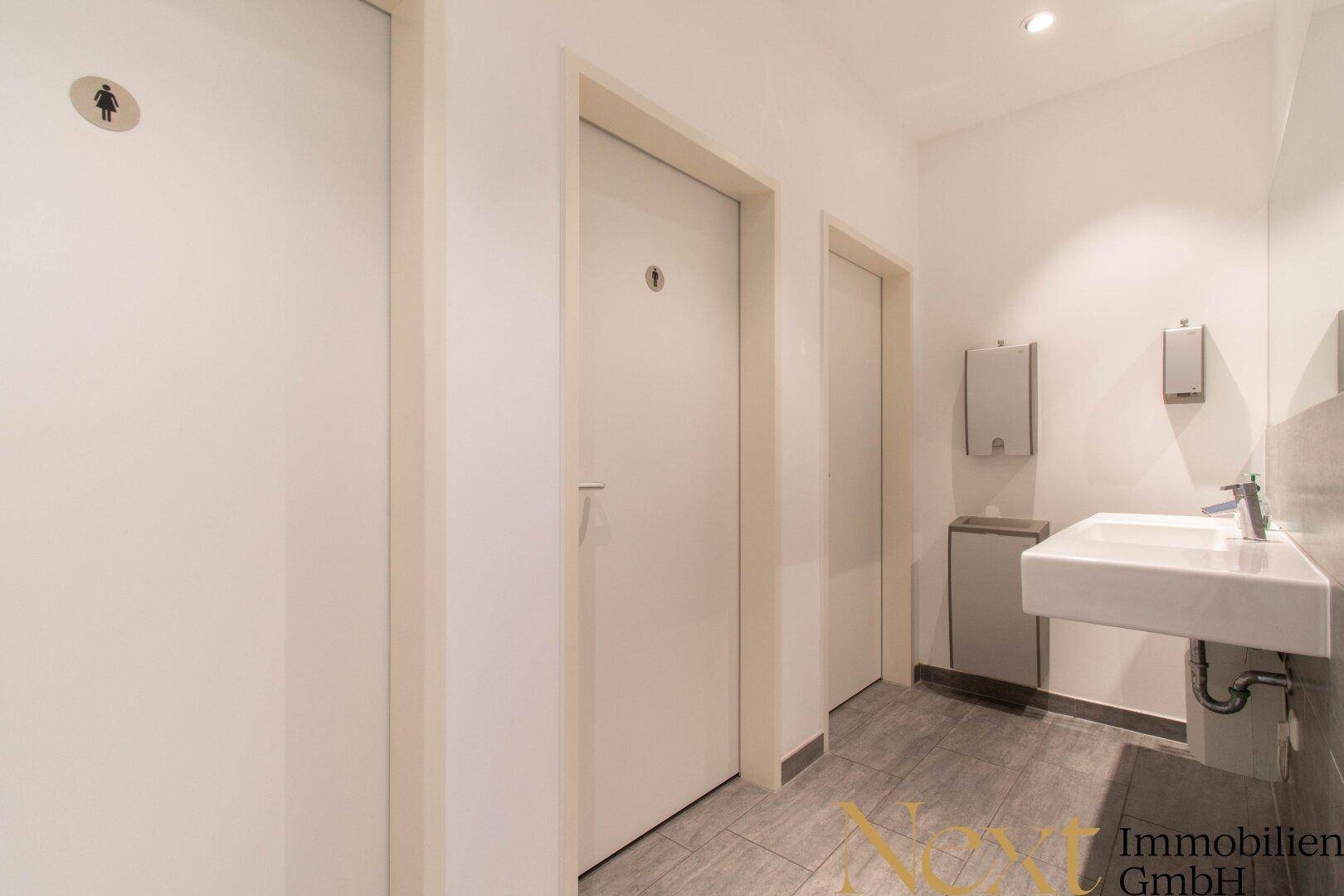 Sauberer Toilettenbereich mit mehreren Kabinen, einem Waschbecken und einem Spiegel für die Gäste.
