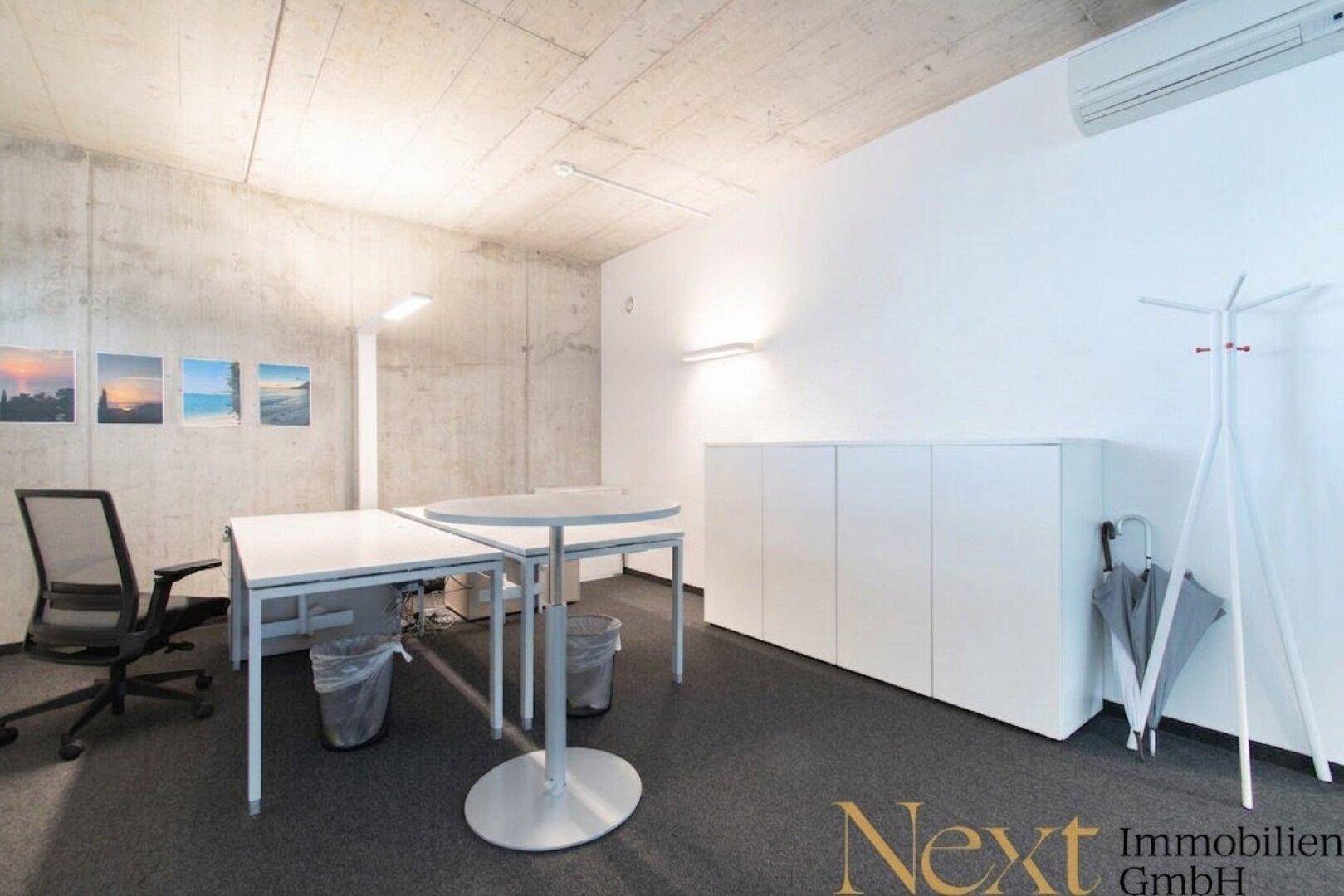 Flexibler Bürobereich mit Stehtischen, Bürostuhl, weißen Schränken und einer Garderobe für Mitarbeiter.