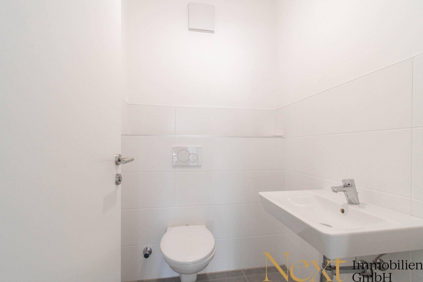 Modernes Gäste-WC mit weiß gefliesten Wänden, wandhängendem WC und Waschbecken.